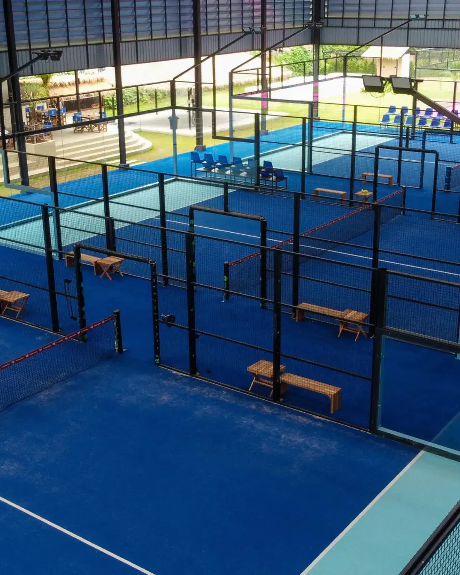 Interior view of Padel Tropical's covered padel courts with blue surfaces under a high roof