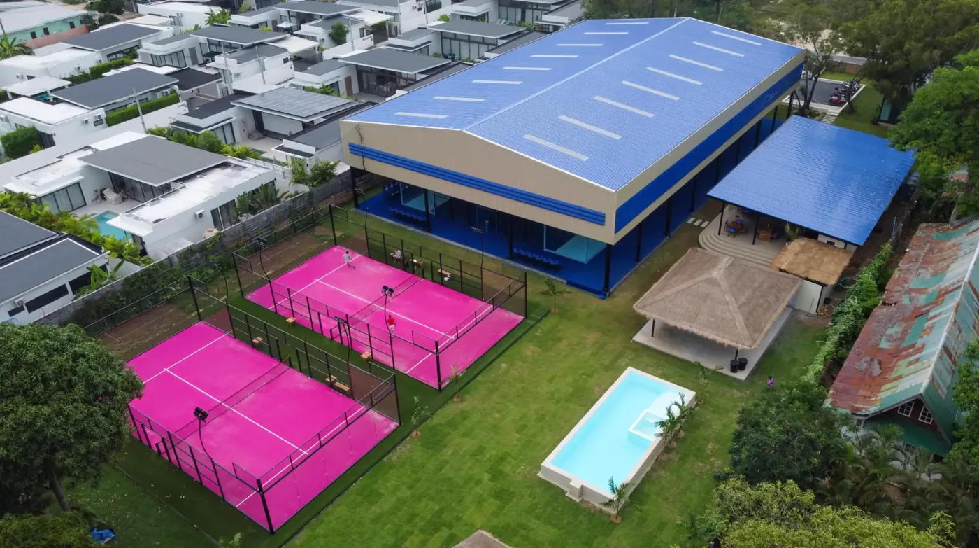 Aerial view of Padel Tropical club with pink outdoor courts and pool in Koh Samui