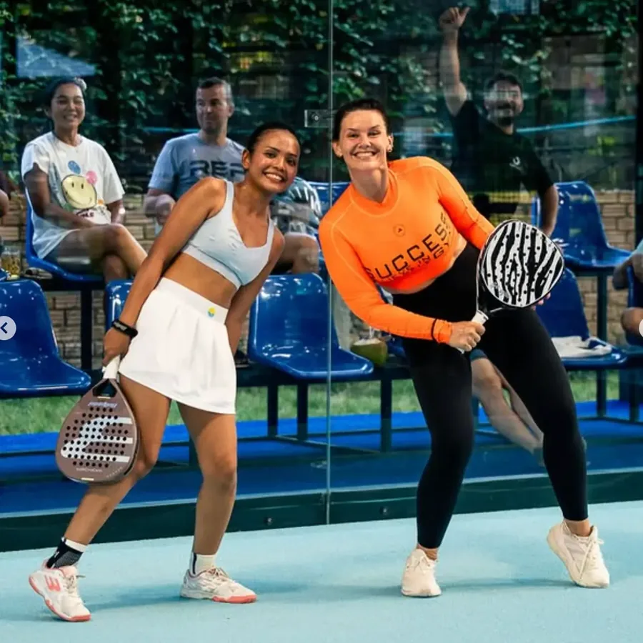 Two players posing with rackets during a fun doubles match at Padel Tropical